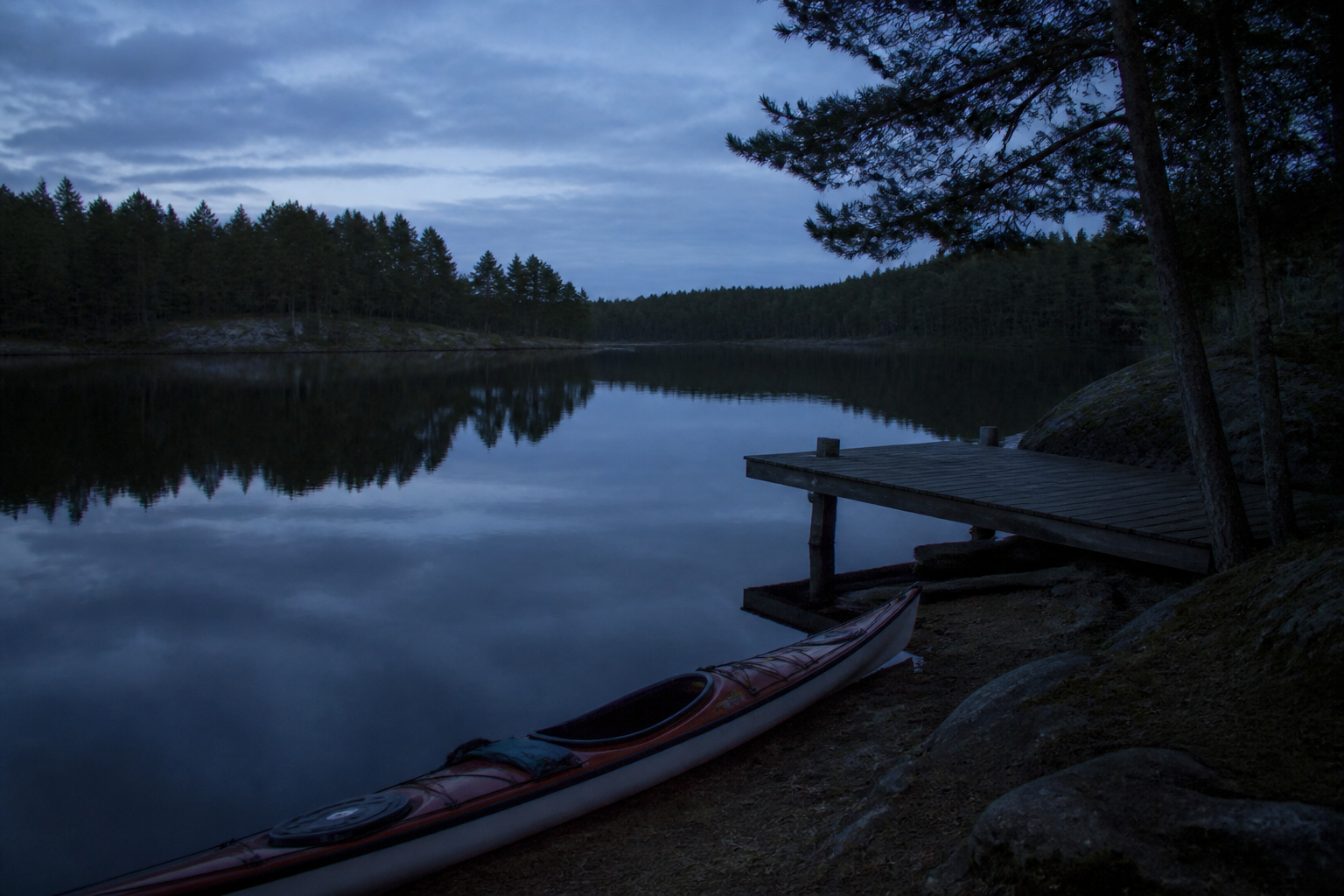 Still northern lake at blue hour, a kayak on the dock